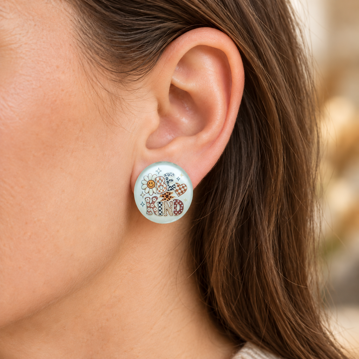 Mintfarbene 20-mm-Ohrstecker mit „BE KIND“, Blume und Herz am Ohr einer Frau.