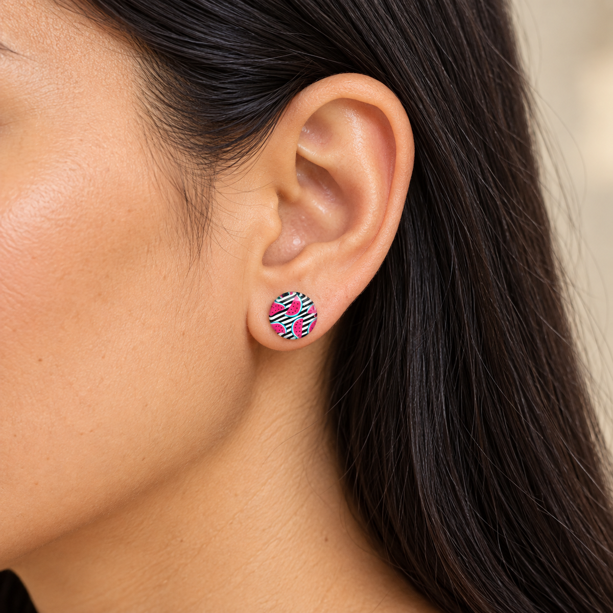 10-mm-Ohrstecker mit pinken Melonen auf schwarz-weißen Streifen am Ohr einer Frau mit schwarzen Haaren.