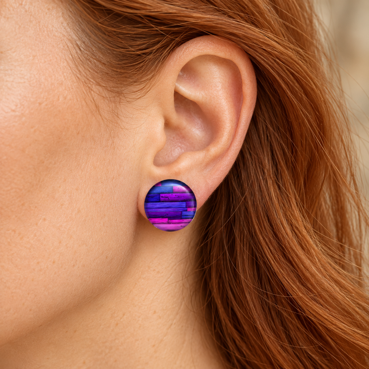 20-mm-Ohrstecker mit violettem Holzdekor-Motiv am Ohr einer Frau mit langen roten Haaren.